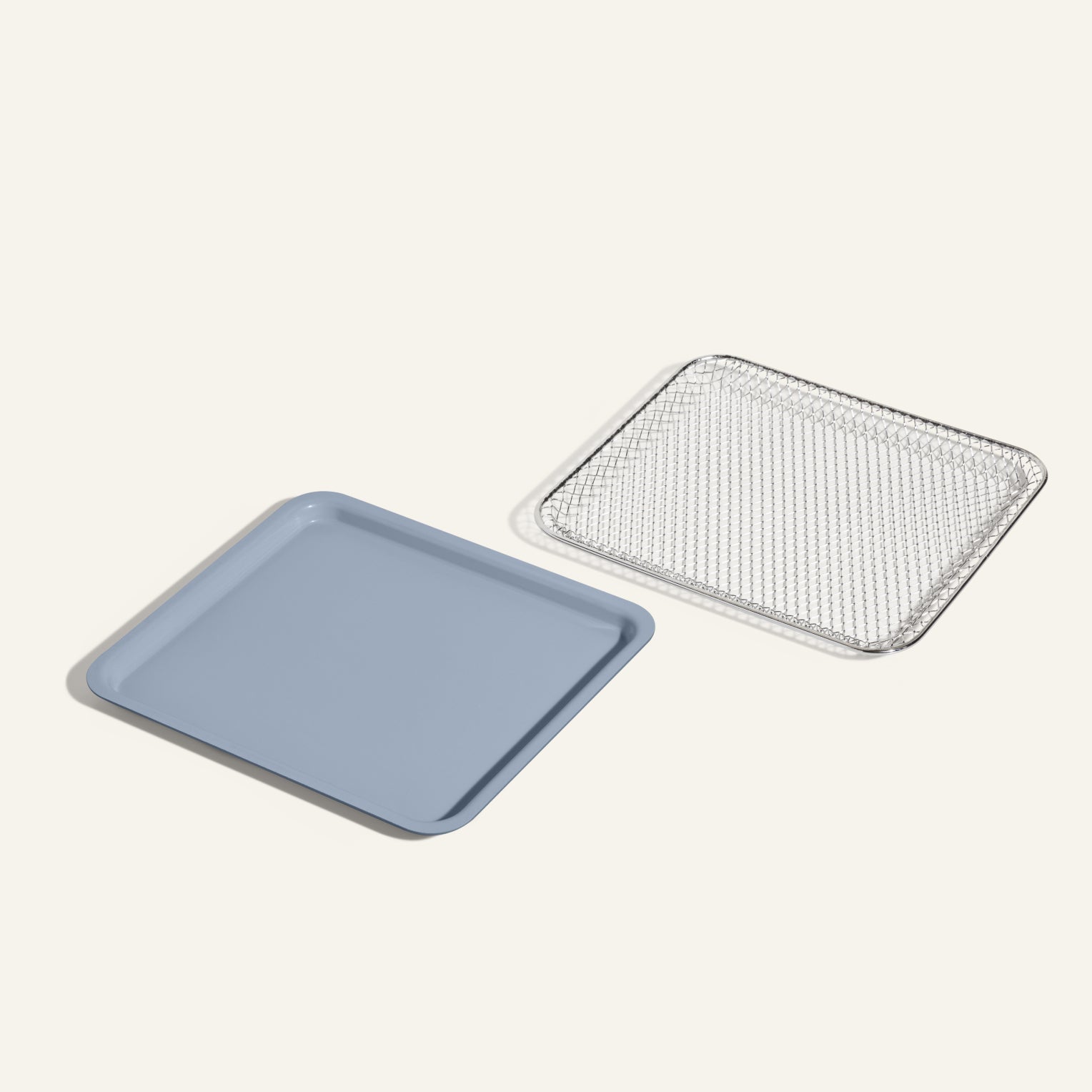 The Wonder Oven Essentials Kit, featuring a light blue square baking tray and a matching silver wire cooling rack, is displayed side by side on a neutral background—ideal for doubling recipes or upgrading your Wonder Oven.