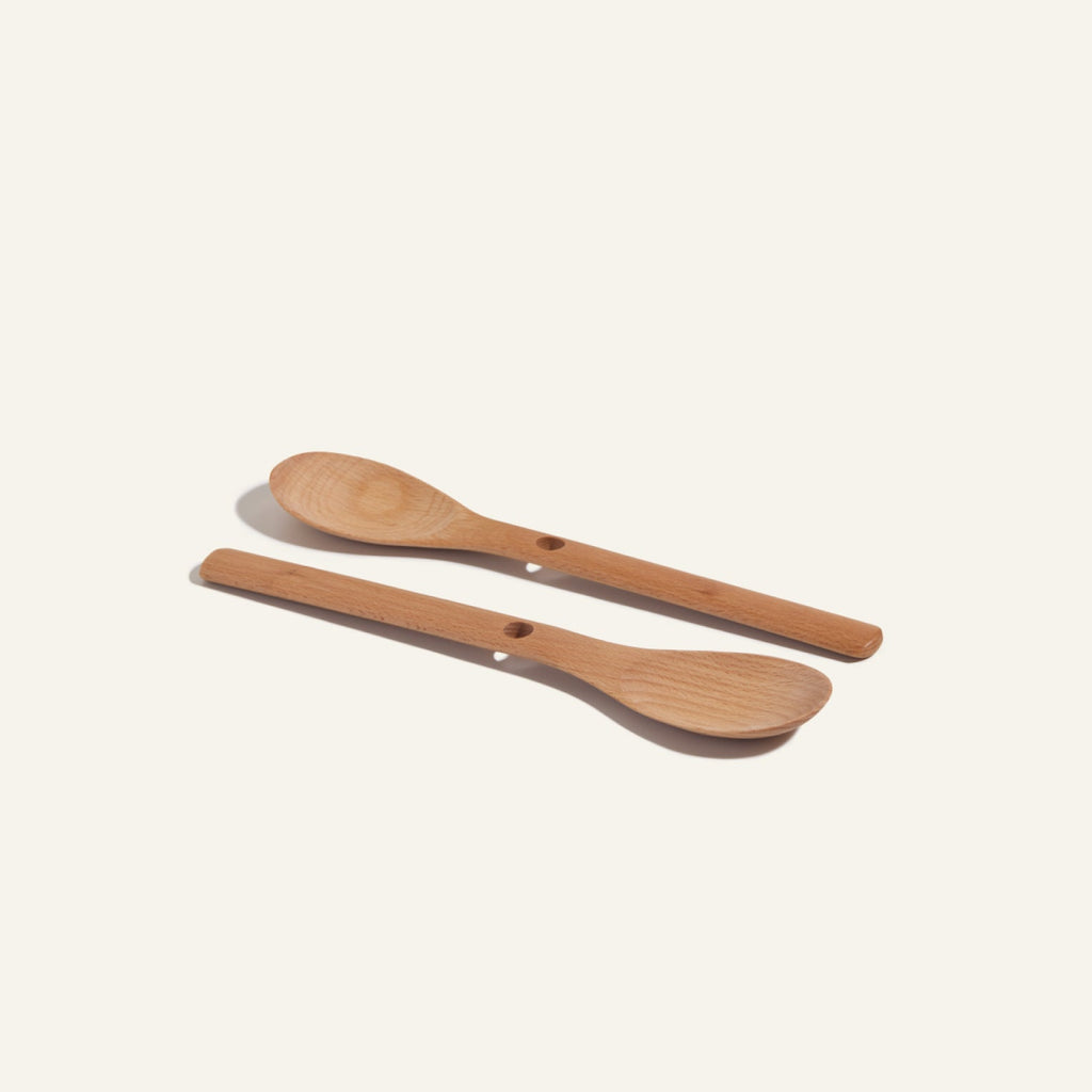 Two Beechwood Spoons with holes in the handles are placed side by side on a light background, making them ideal kitchen utensils for everyday use.