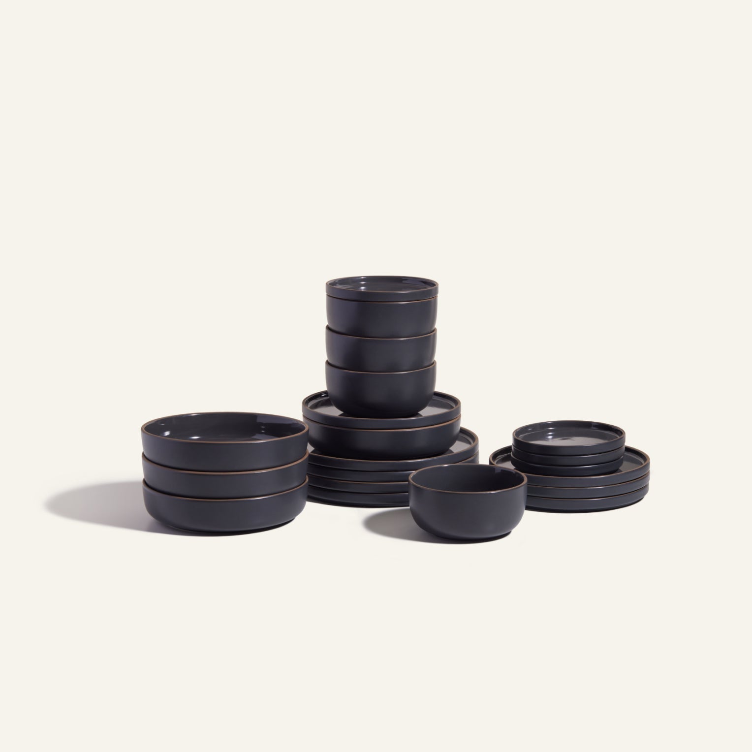The Classic Stacking Set is a 20-piece matte black ceramic tableware collection with scratch-resistant plates, bowls, and small dishes, neatly arranged on a plain light background.