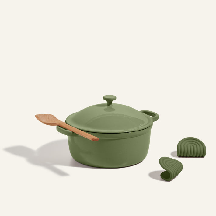 Cast Iron Perfect Pot with green lid and wooden spatula on top, paired with two green silicone oven mitts, all displayed on a plain light background.