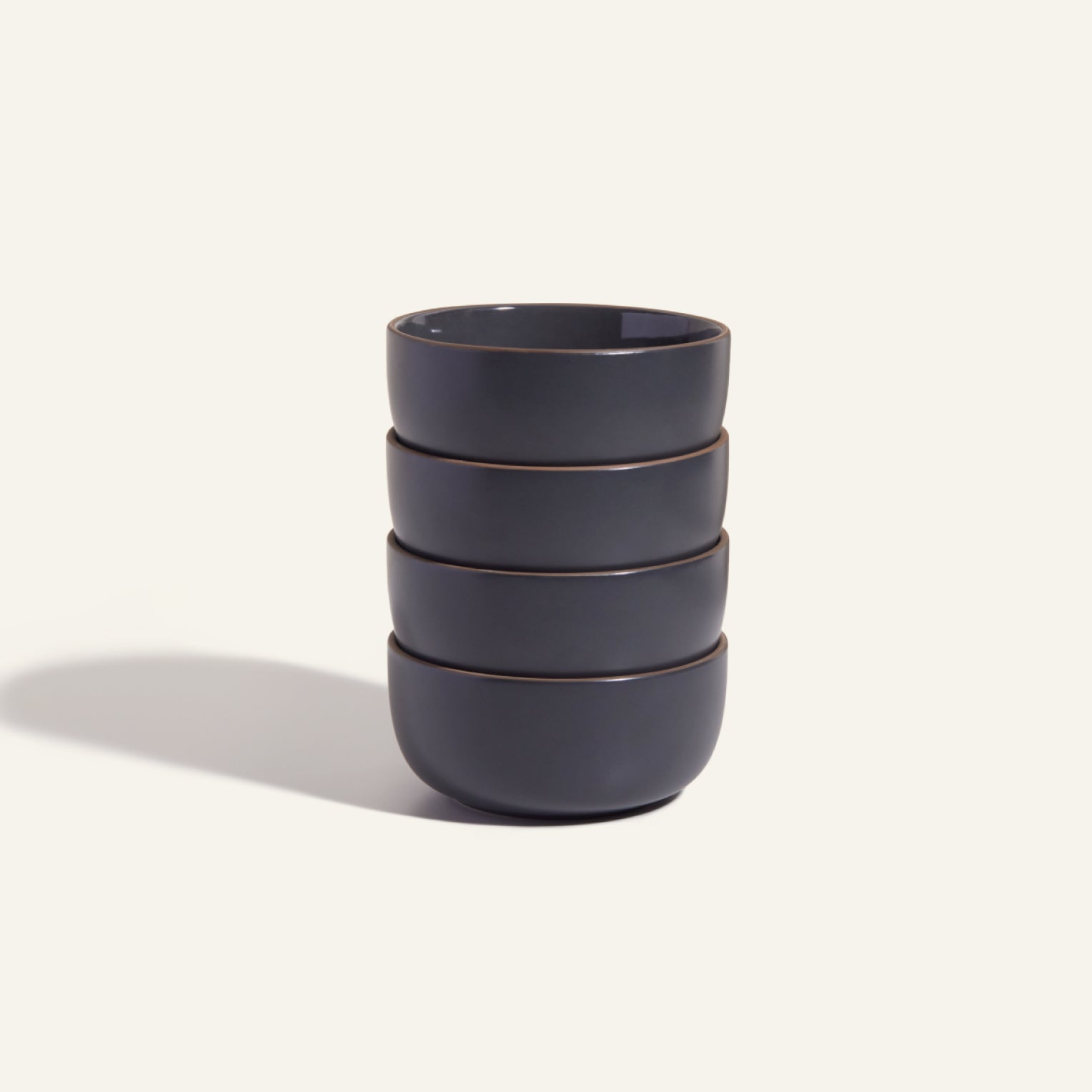 Four dark grey Soup Bowls are stacked vertically against a plain light background, highlighting a modern bowl set ideal for stylish tableware.