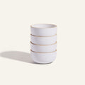 Four Soup Bowls with white ceramic bodies and light brown rims are stacked together against a plain, light background, highlighting a stylish addition to your tableware collection.