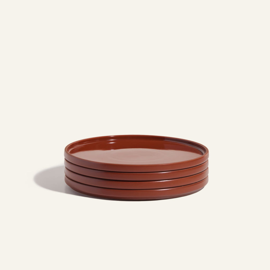 A stack of four round, glossy, reddish-brown hand-glazed Dinner Plates on a plain light background—an elegant addition to any ceramic set or tableware collection.