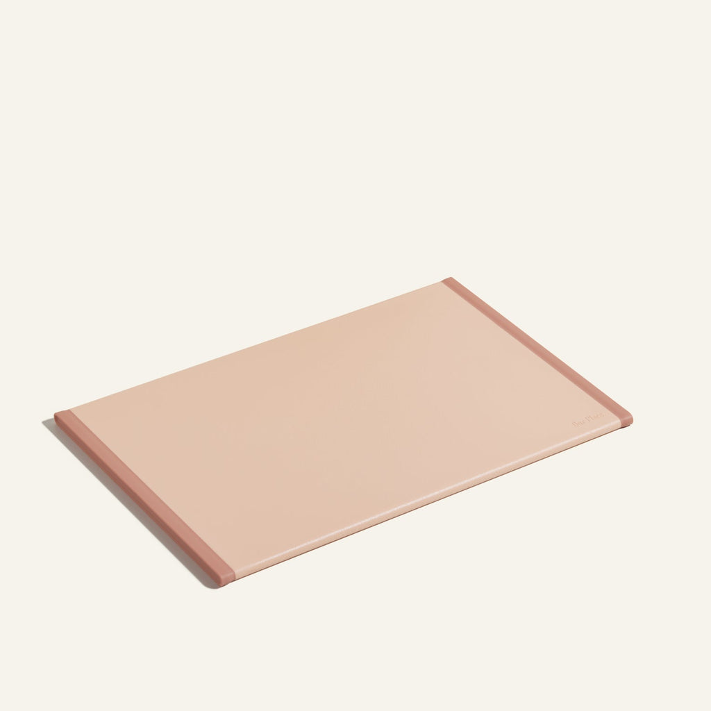 The Daily Board, a rectangular light pink cutting board with darker pink edges made from recycled materials, is displayed on a plain light background.