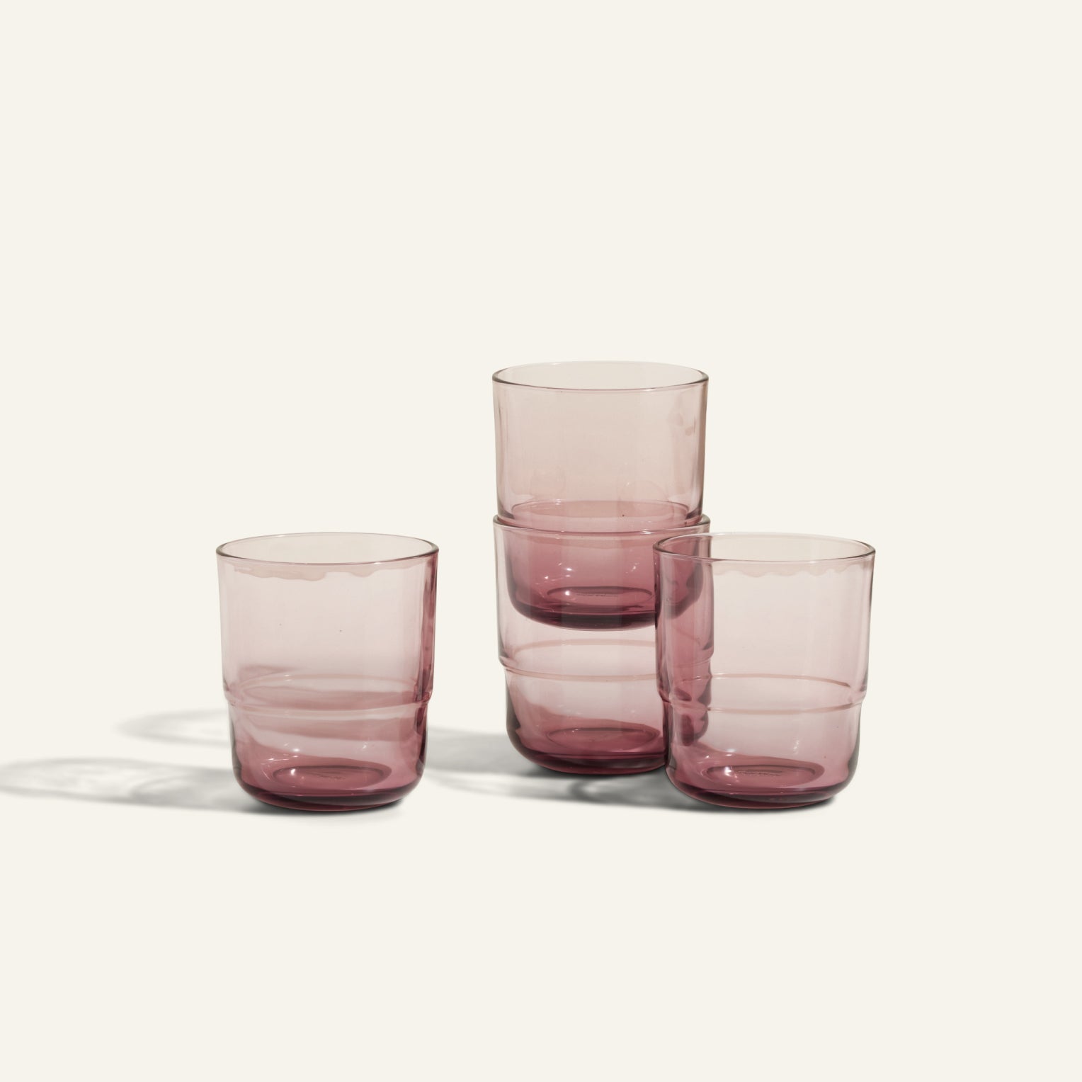 Four Short Night + Day Glasses, each with a purple tint and handmade design, are arranged in a staggered stack on a light background.