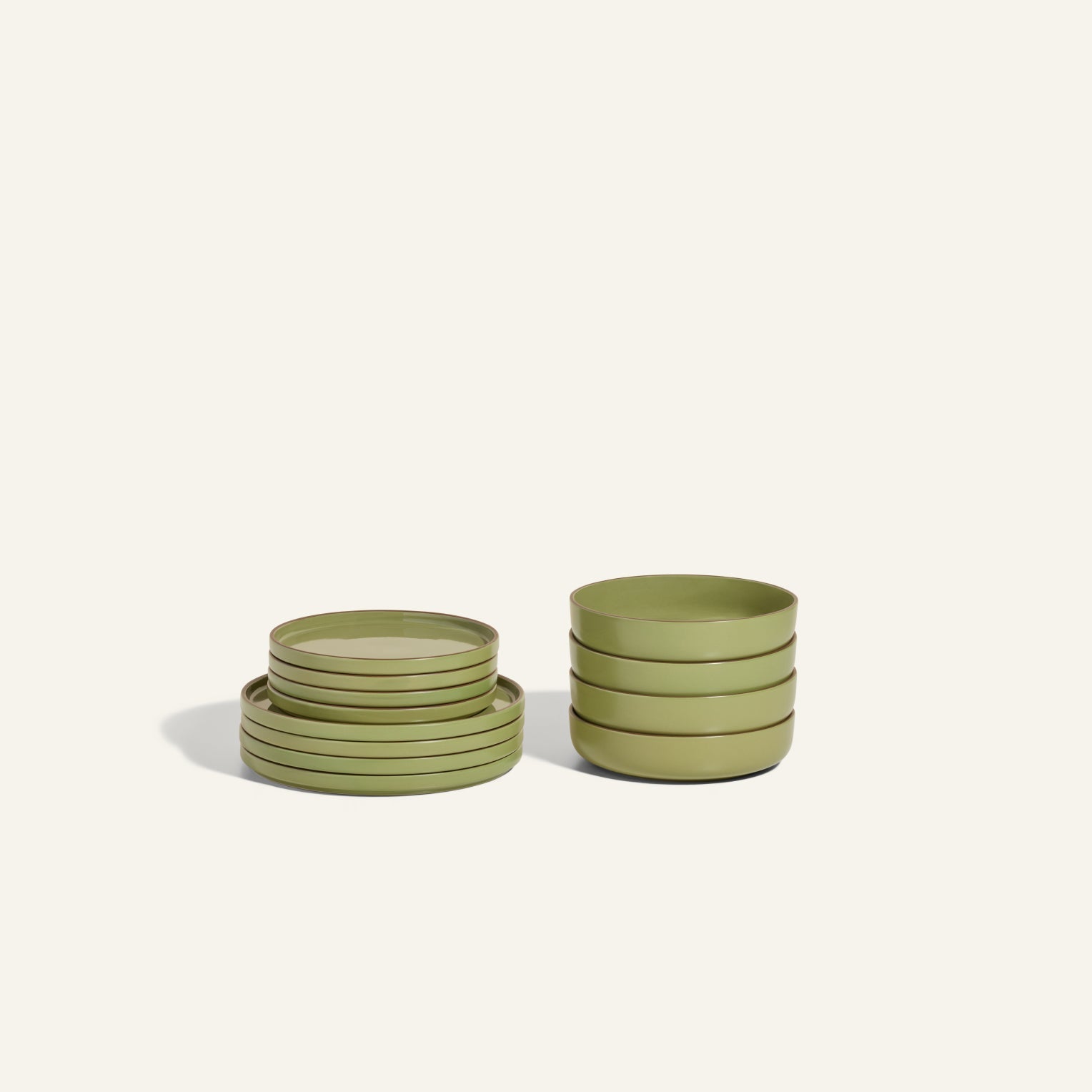 Two stacks from the Starter Stacking Set in matte olive green—one of hand-glazed plates, one of bowls—are shown on a light background, perfect for discerning kitchen owners.
