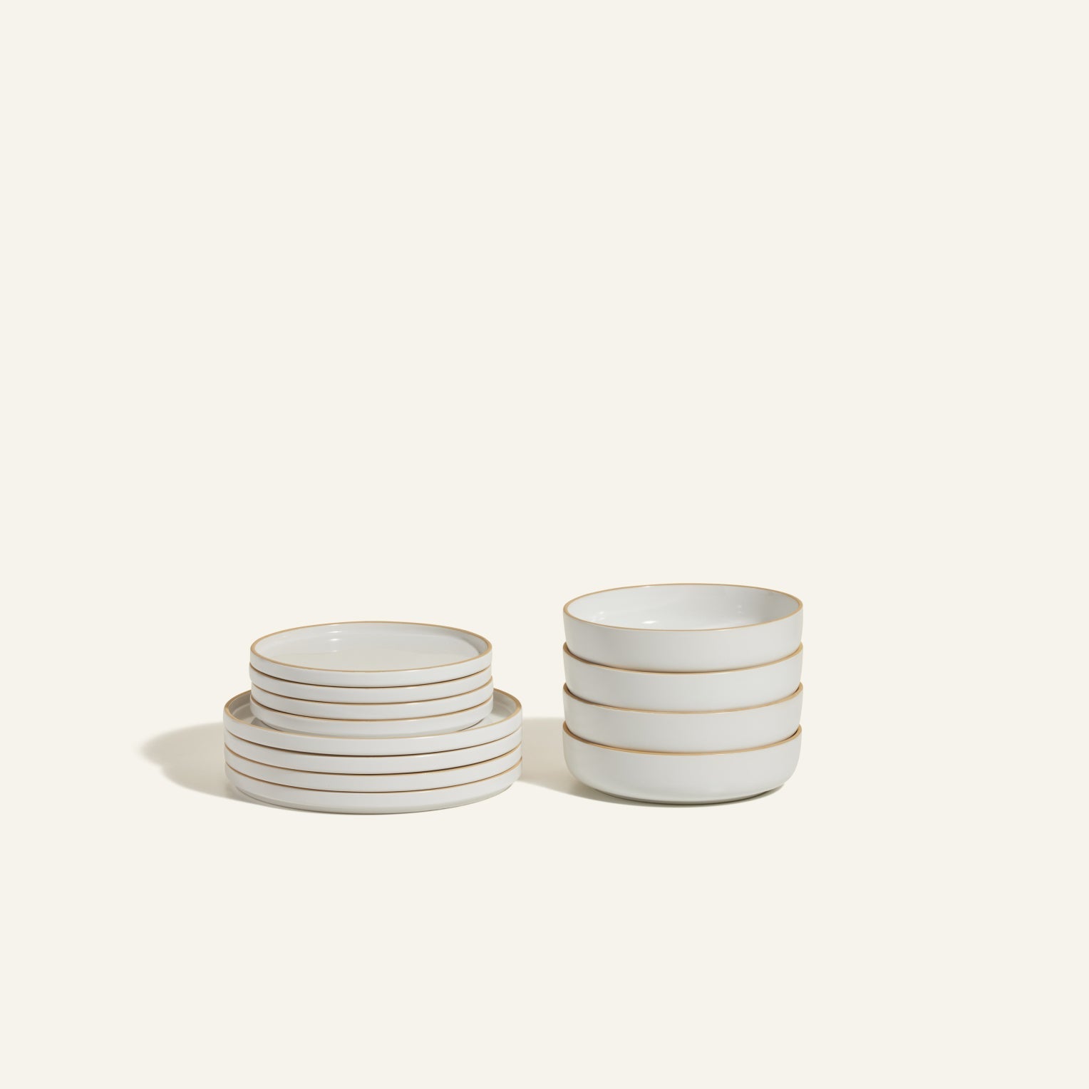 The Starter Stacking Set features hand-glazed plates and bowls with elegant beige rims—perfect for kitchens seeking timeless style, shown against a plain light background.