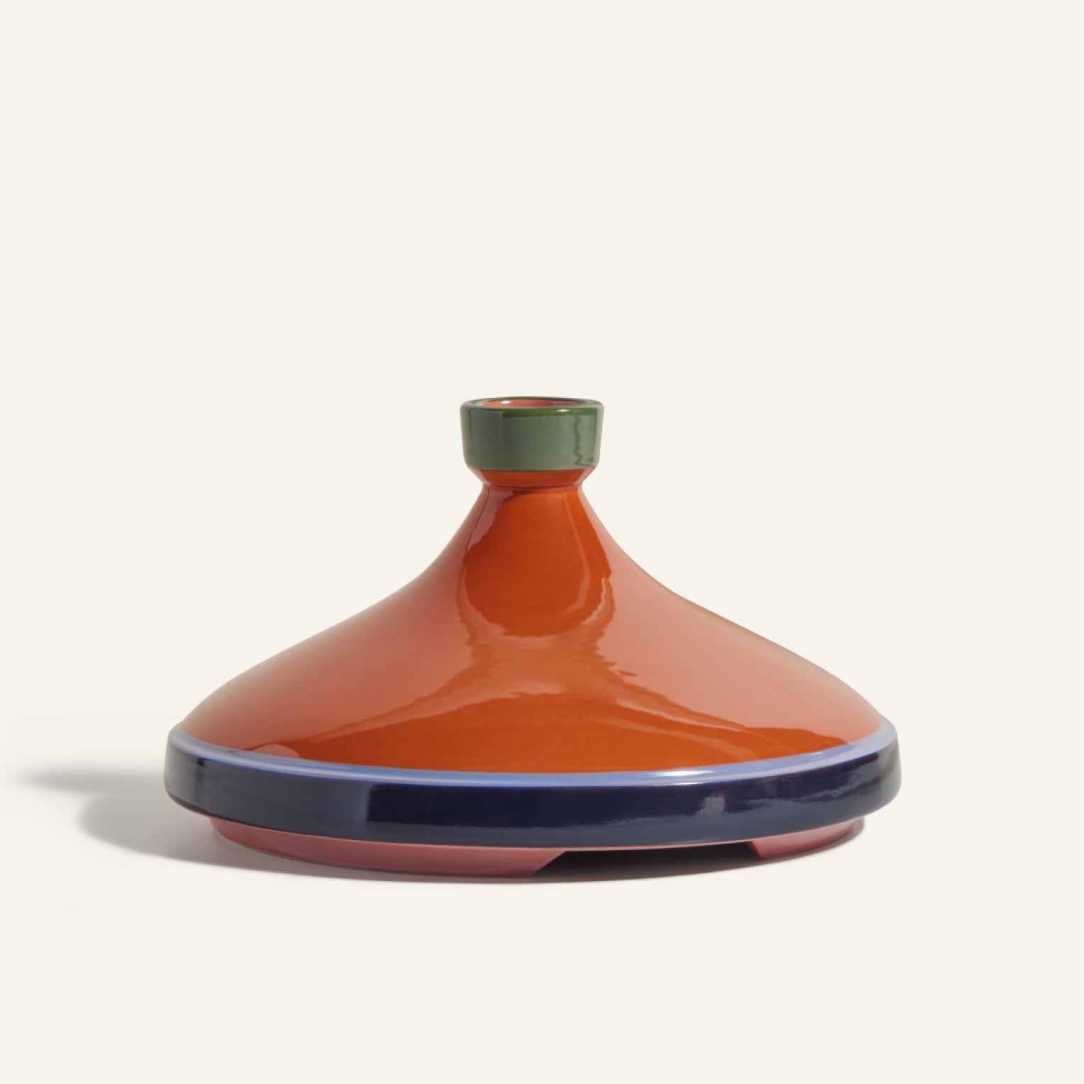 A handcrafted Tagine with a conical orange lid, green knob, and blue base rim—ideal for slow cooking—is displayed on a neutral background.
