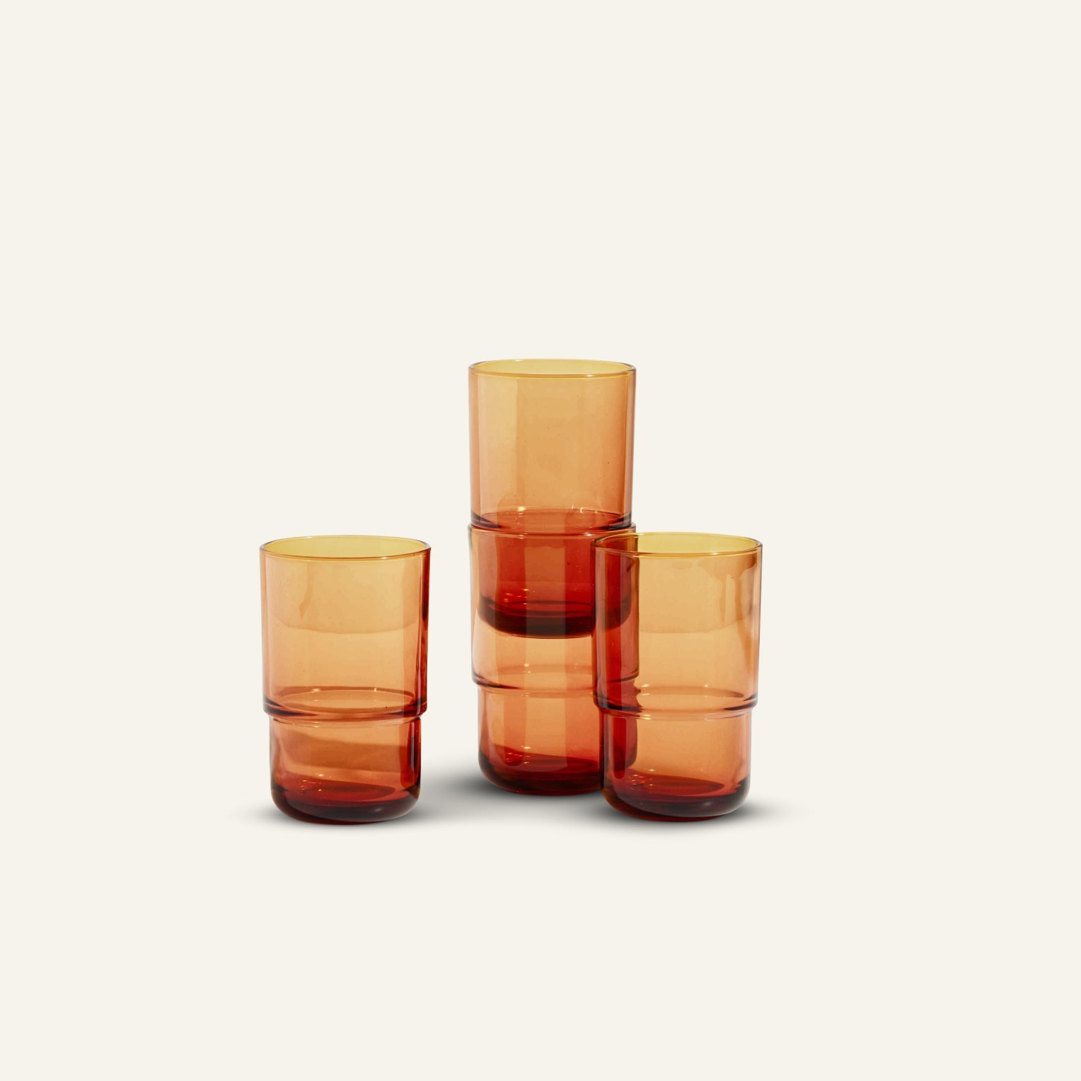 Four Tall Night + Day Glasses are displayed—two stacked, two beside them—against an off-white background. Each 16 oz amber tumbler features a handmade touch, giving every piece a unique look.