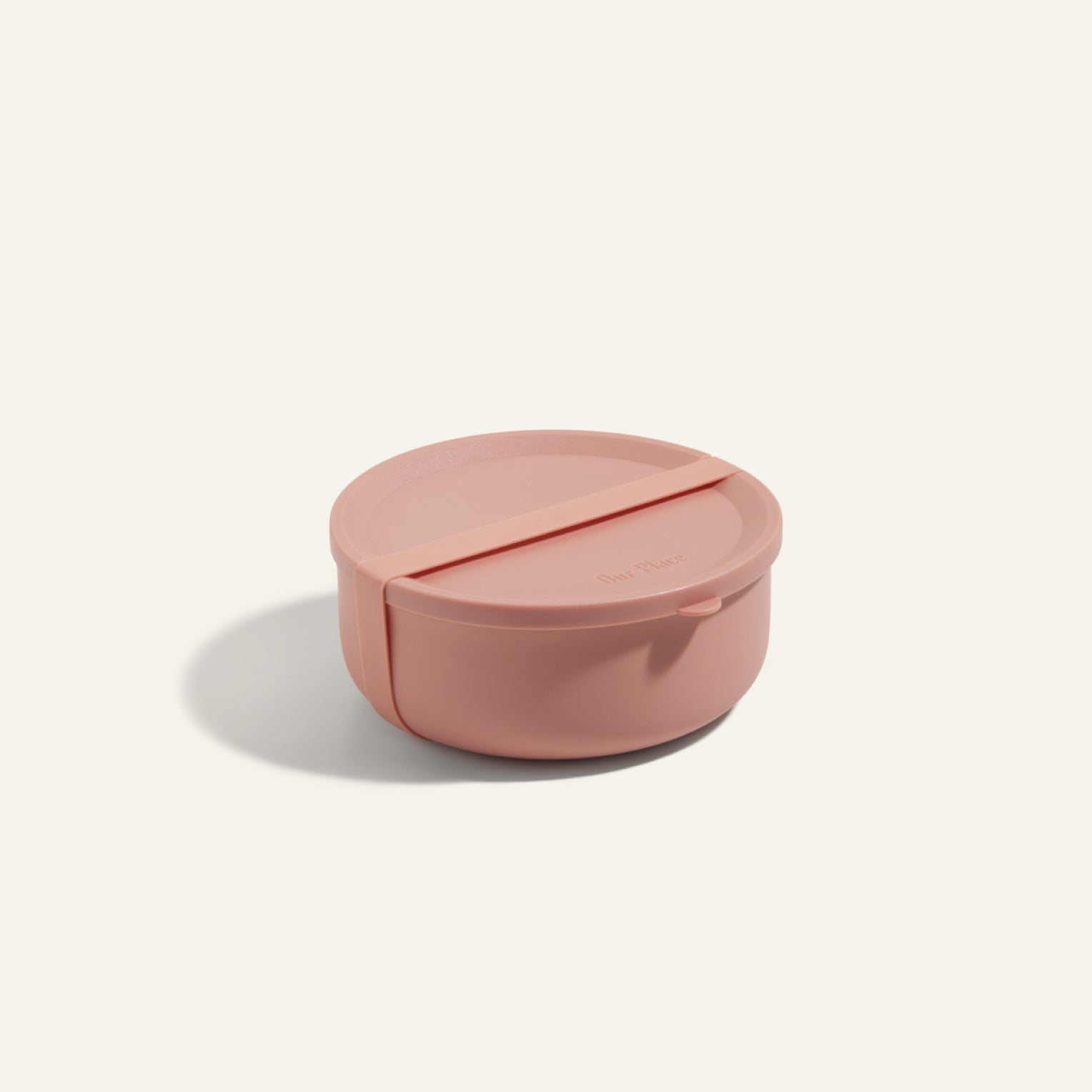 The Wander Bowl, a round pink lunch container with a matching lid, is shown on a plain background. This microwave-safe solution keeps your meals fresh and ready to enjoy.