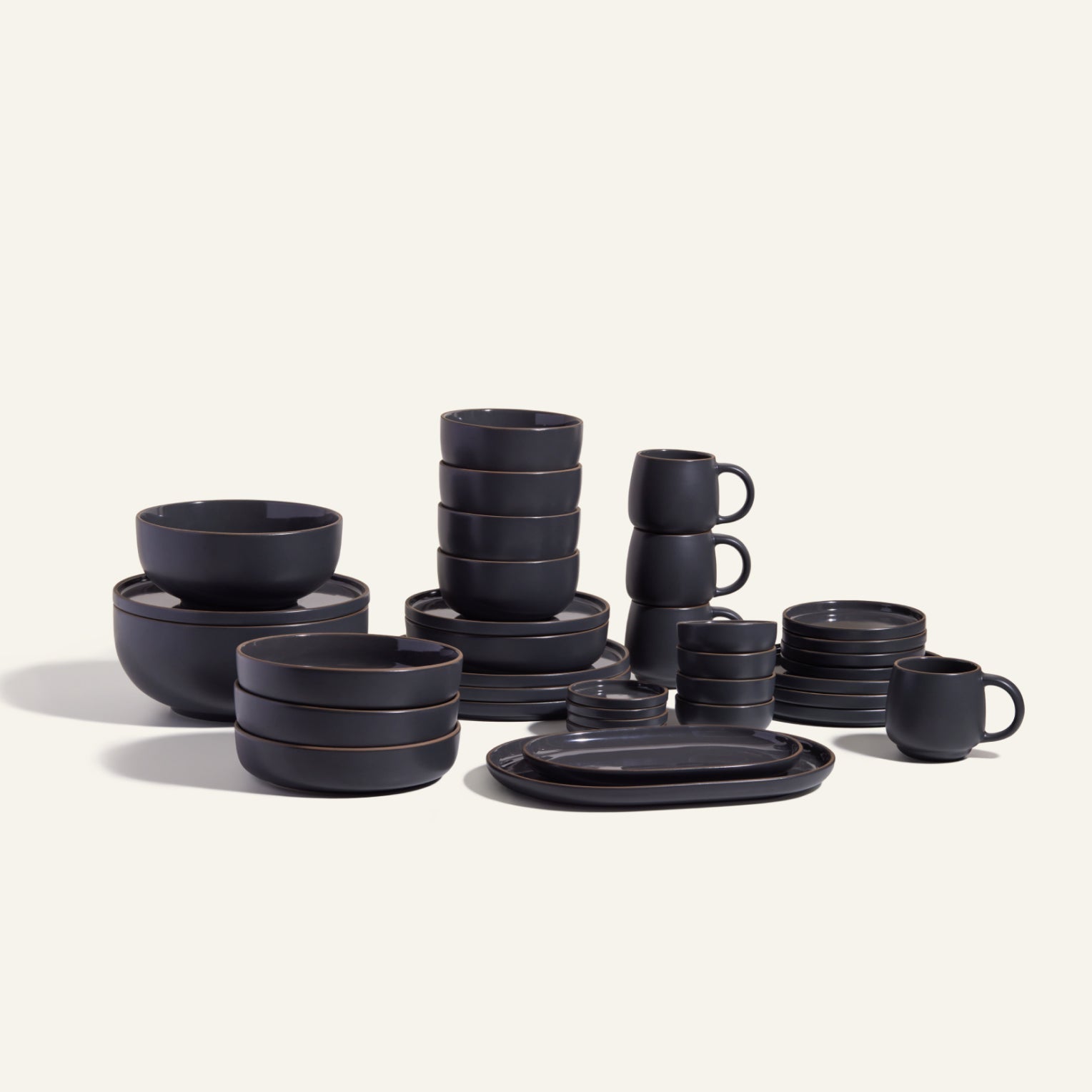 The Complete Stacking Set features matte black ceramic bowls, plates, and mugs arranged on a light background—an ideal, stylish hosting set for any occasion.