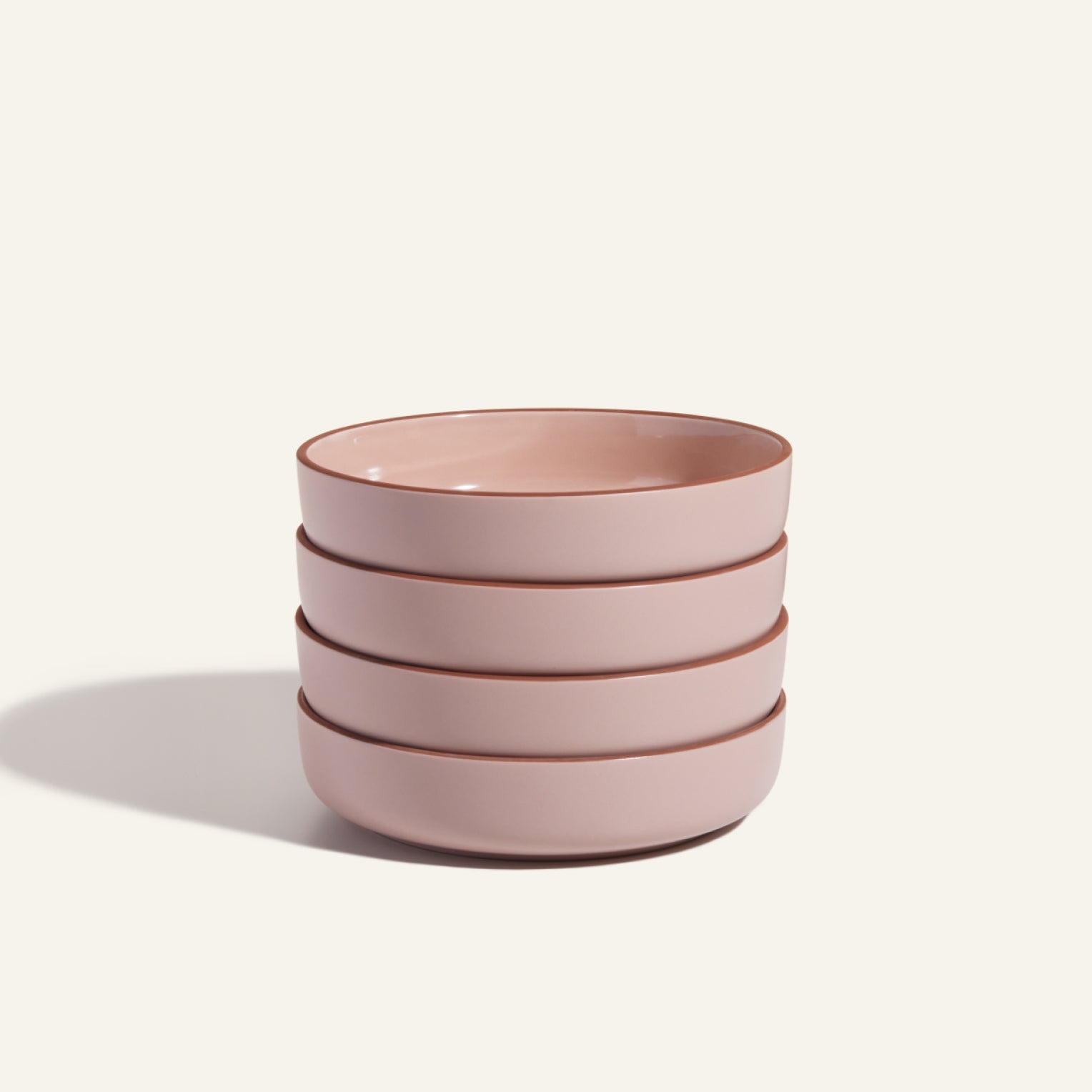 A stack of four pink, scratch-resistant Dinner Bowls sits against a plain background—stylish, stackable tableware perfect for any modern kitchen.