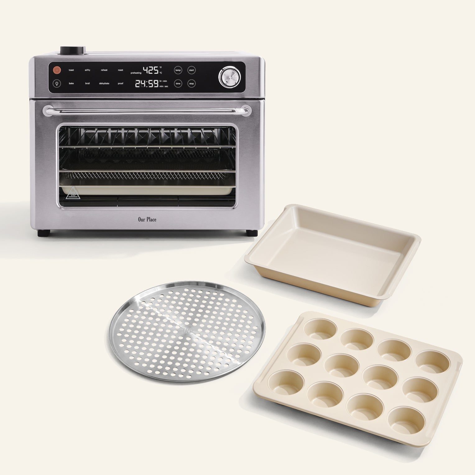 The Wonder Oven Pro + Wonder Oven Pro Chef's Kit, a stainless steel countertop oven with digital controls, is shown with a muffin tin, square baking pan, and round perforated tray on a light background.