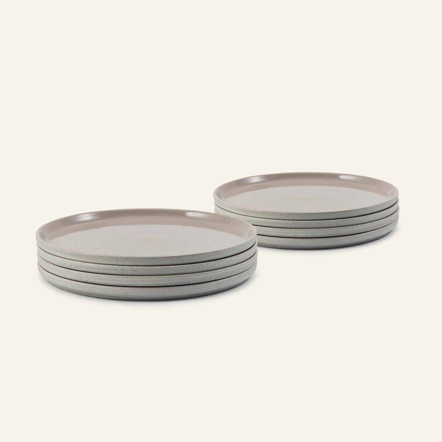 Two stacks of Main Plates, each with four dishwasher-safe dishes featuring a light speckled gray finish and gently raised rims, arranged on a neutral background.