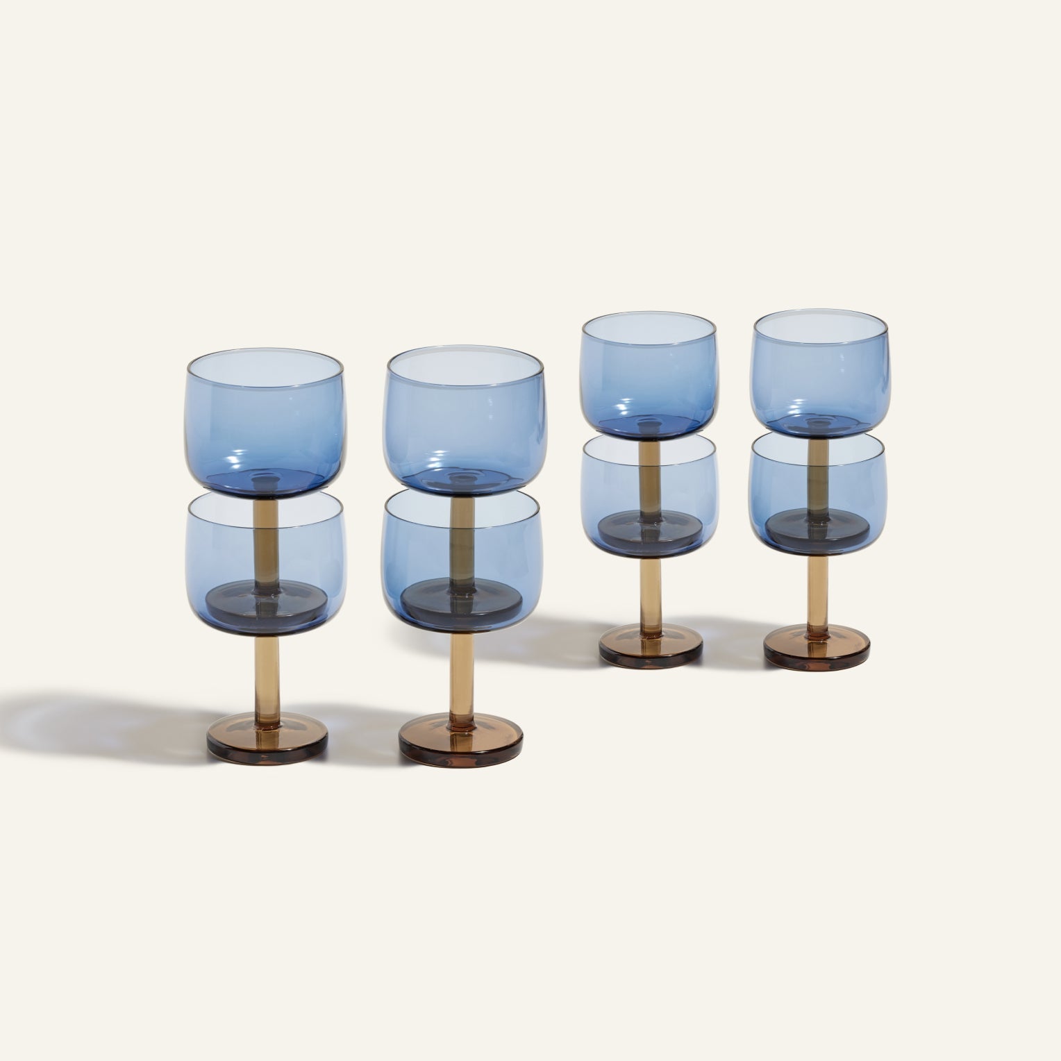 Six modern blue Party Coupes with cylindrical brown stems are arranged in two rows on a light background, creating a striking and stylish set of party glassware.