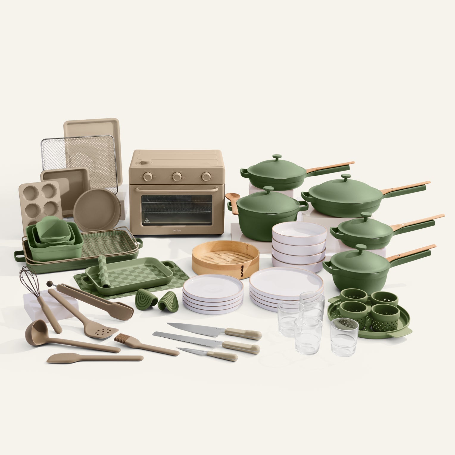 Collection of green kitchenware including pots, pans, and utensils on a white background