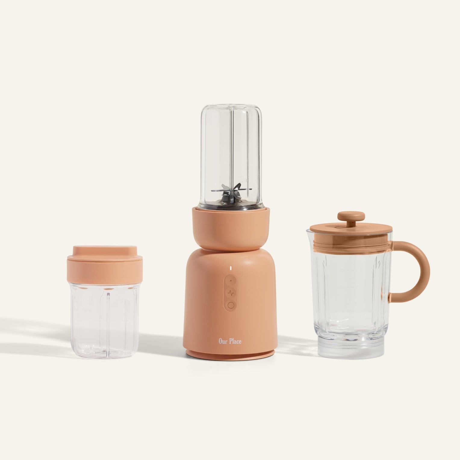 The Splendor Blender + Splendor Blender Everything Kit features a compact blender with a tan base and includes two clear blending containers: a small one with a lid and a large one with both a handle and lid, set against a light background.