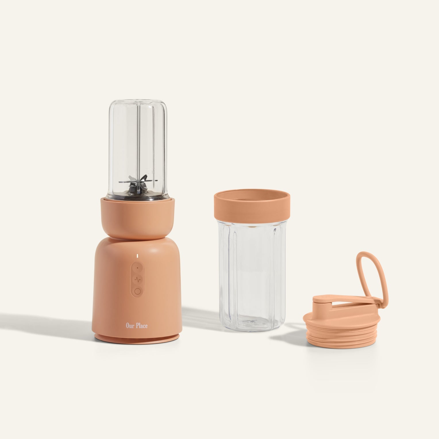 The Splendor Blender with a peach base, blending cup attached, empty glass jar with lid, and an extra lid with carrying handle from the Splendor Blender Personal Kit are shown on a light background.