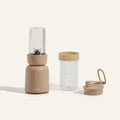 The Splendor Blender + Splendor Blender Personal Kit features a beige personal blender with an attached blending jar, an extra clear jar, and a matching handled lid, all displayed on a neutral background.