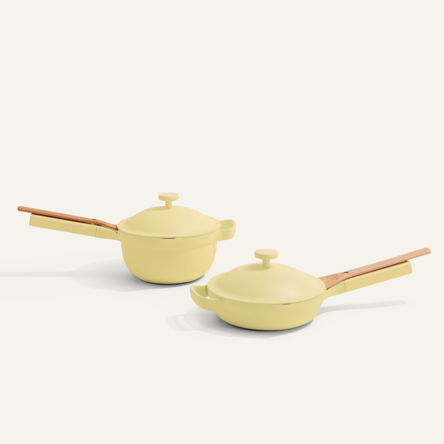 Two yellow cookware items with wooden handles on a white background