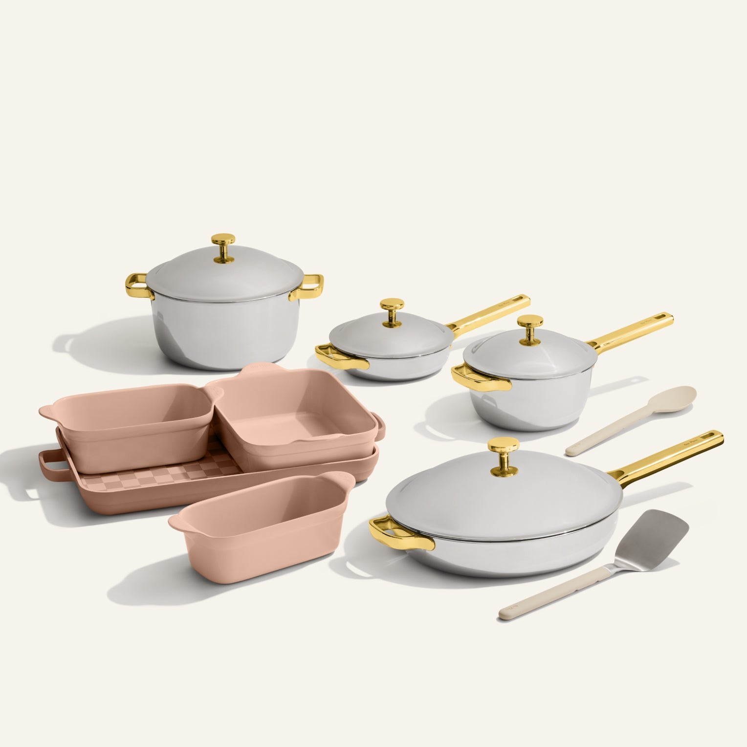 The VIP Titanium Pro Complete Cookware + Bakeware Set includes white titanium pots with gold handles, pink nonstick bakeware, a spatula, and a spoon, all beautifully arranged on a light background.