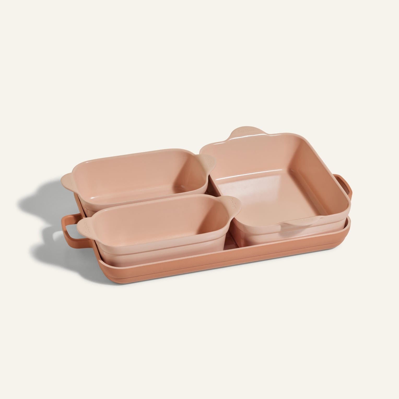 The Bakeware Set includes four pink ceramic baking dishes in different sizes, neatly nested together on a light background, offering both style and practicality for your kitchen.