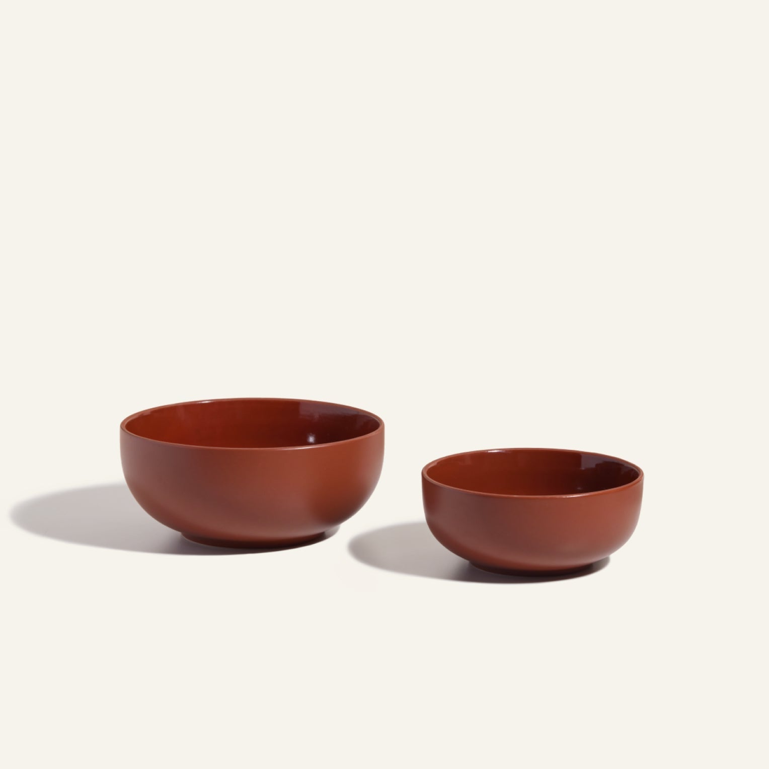 Two Serving Bowls in different sizes, featuring a smooth reddish-brown finish, are displayed side by side on a light background—ideal as stackable tableware for your kitchen.