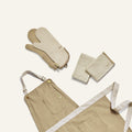 Beige apron, oven mitts, and pot holder on a light beige background